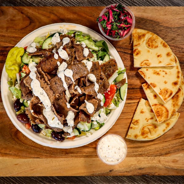 Niro's House Mediterranean Kitchen's gyro salad with pita bread, pickled vegetables, and tzatziki sauce.