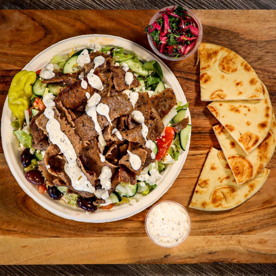 Niro's House Mediterranean Kitchen's gyro salad with pita bread, pickled vegetables, and tzatziki sauce.
