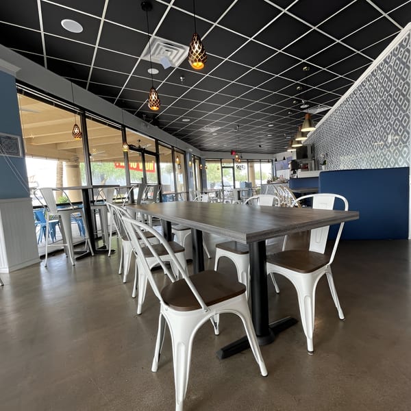 Niro's House Mediterranean Kitchen dining room with white chairs, dark tables, and blue booth seating.