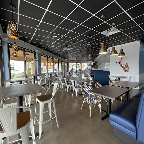 Interior of Niro's House Mediterranean Kitchen, featuring modern tables, chairs, blue booths, and decorative lighting.