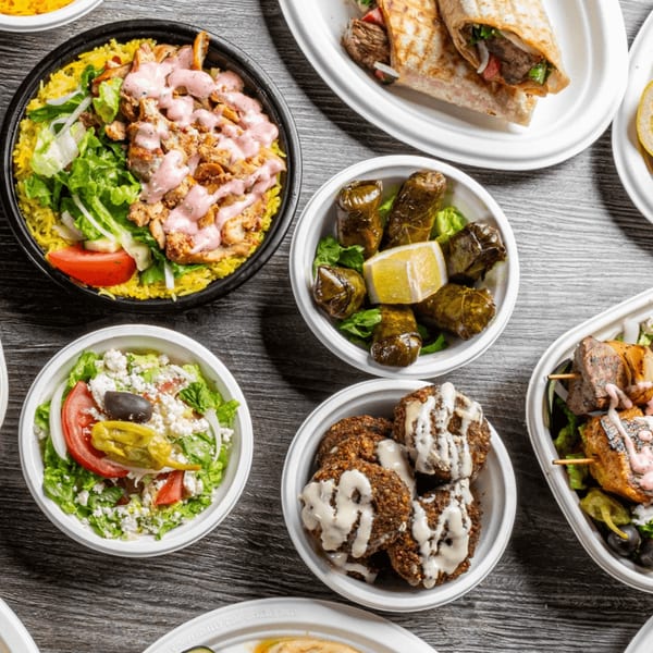 Overhead view of various Mediterranean dishes including shawarma, falafel, grape leaves, and salad.