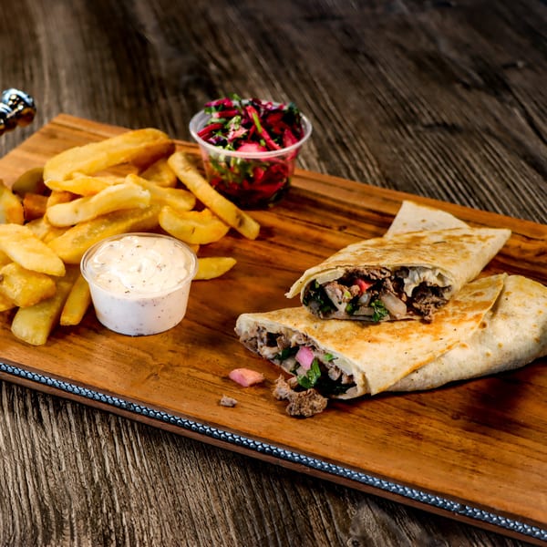 Two Mediterranean wraps with meat and vegetables, served with fries, dipping sauce, and a side salad.
