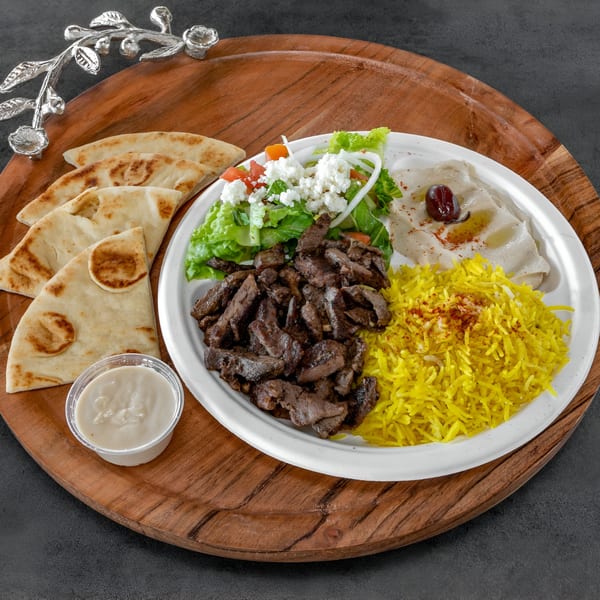 Niro's House Mediterranean Kitchen's beef shawarma plate with rice, salad, hummus, pita bread, and sauce.